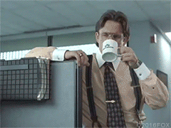 Bill Lumber, from Office Space, standing, arm resting on an office cubicle wall, slowley sipping coffee.