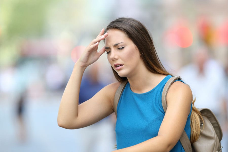 A young woman holds her head in pain.